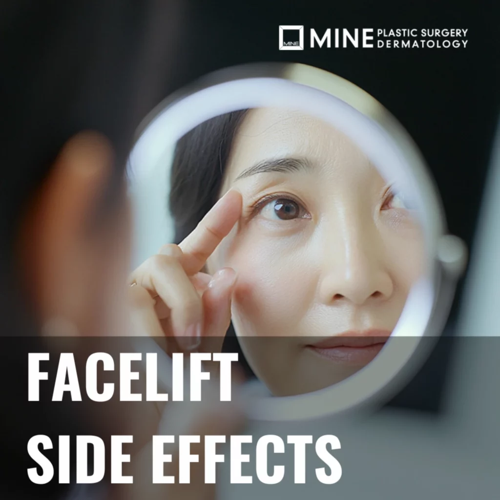 Close-up of a middle-aged woman looking into a handheld mirror while touching her eye area, representing facelift side effects and post-surgery skin concerns at Mine Plastic Surgery.