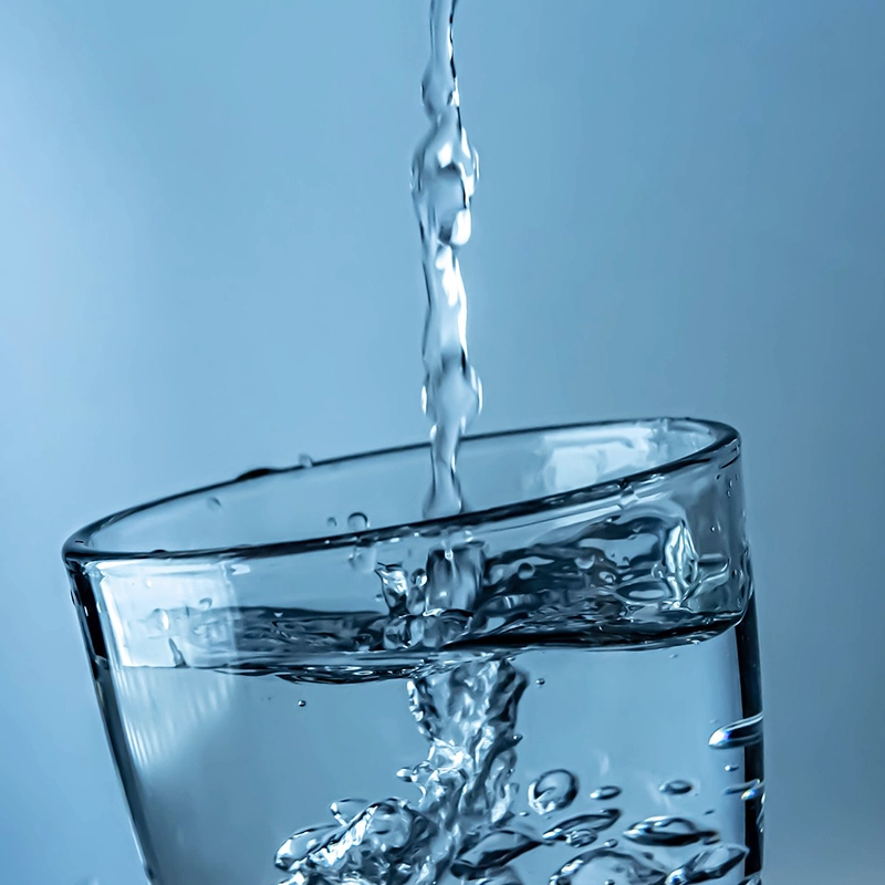 Clear water being poured into a glass, symbolizing hydration and proper self-care during facelift recovery to support healing and skin health.