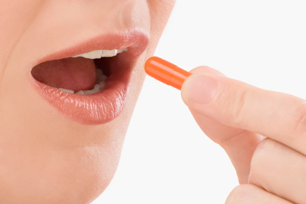 Breast lift recovery medication image showing a person taking an oral capsule, representing prescribed medication use, pain control, and proper postoperative care during breast lift recovery.