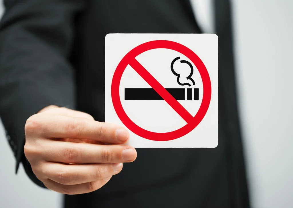 Breast lift recovery guideline image showing a no-smoking symbol held in hand, emphasizing smoking cessation to support proper healing and reduce complications during breast lift recovery.
