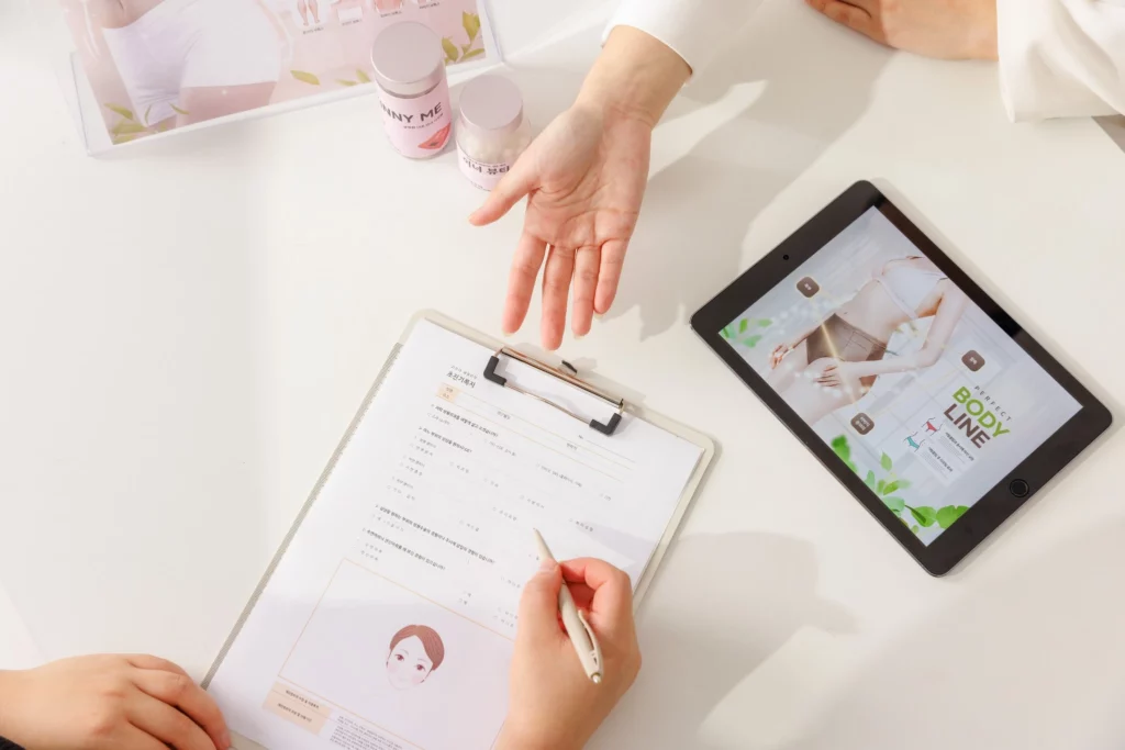 Breast lift surgery consultation scene showing a medical professional explaining a breast lift surgery plan using a tablet and consultation form during a preoperative discussion.