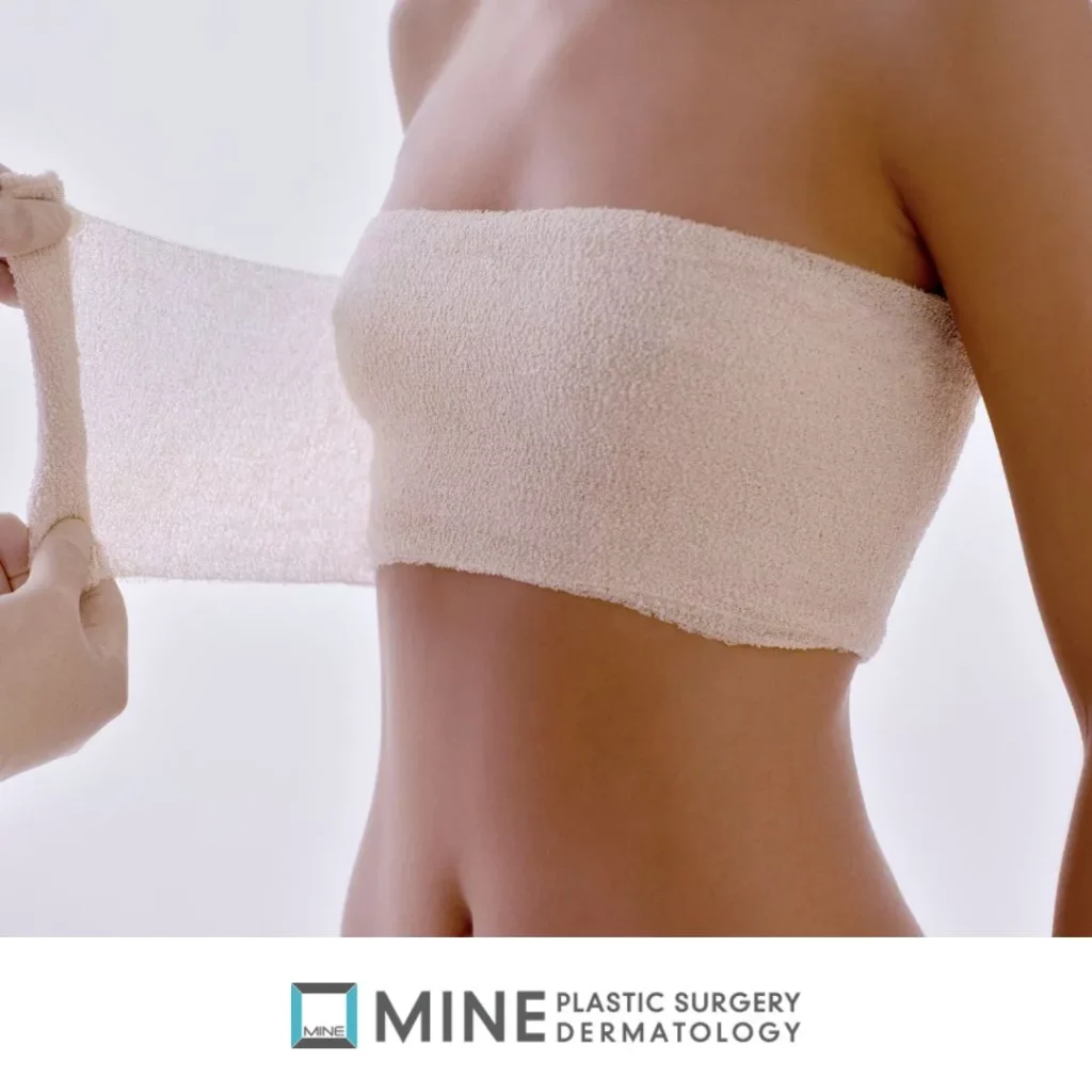 Woman with bandage around chest after breast reduction surgery, showing recovery stage and covering breast reduction scars.