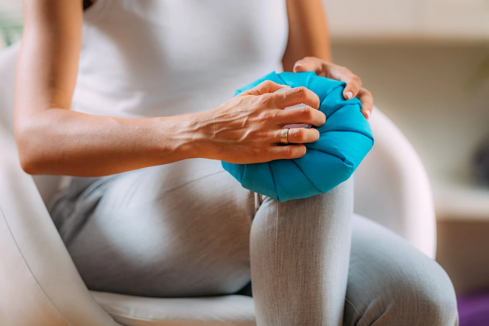 Post surgery numbness illustrated by a patient holding a cold pack on the knee to relieve reduced sensation and discomfort during recovery.