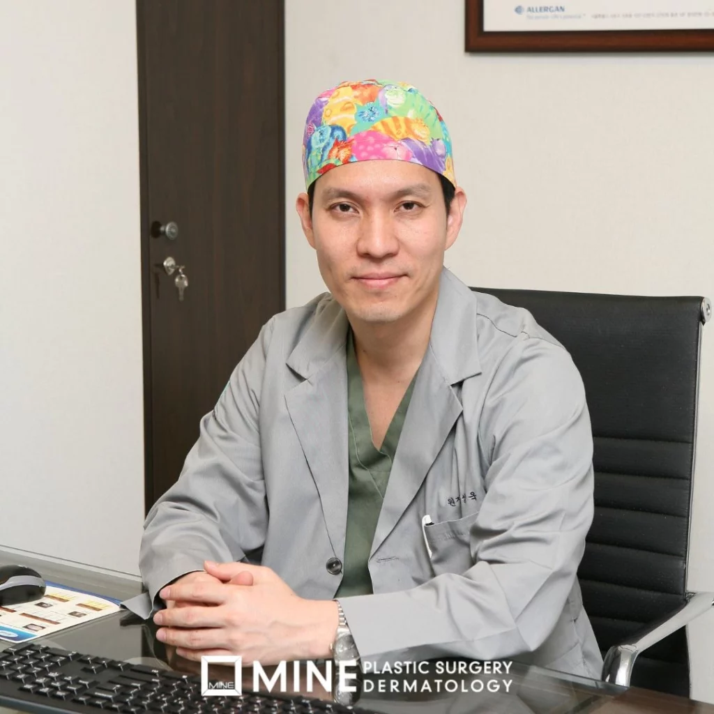 Plastic surgeon seated in a consultation room, representing a specialist who performs hump nose rhinoplasty procedures.