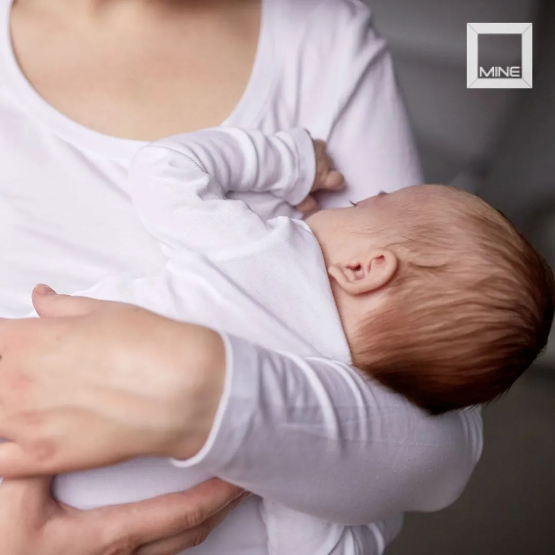 Mother holding her baby while breastfeeding, one of the common reasons women later consider breast lift surgery.