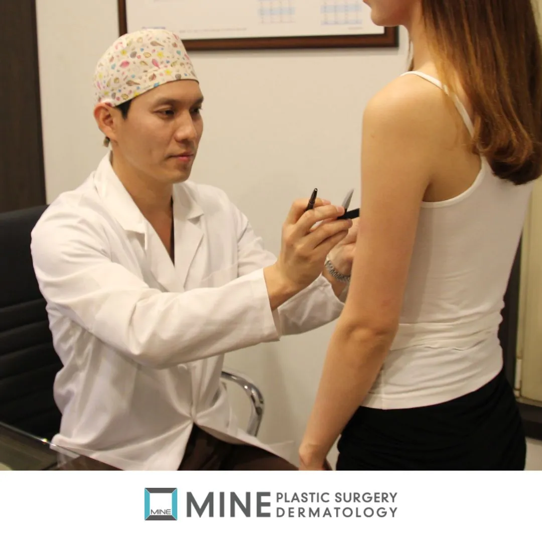 Plastic surgeon examining a patient in the clinic during the pre-operative check that precedes breast lift surgery.