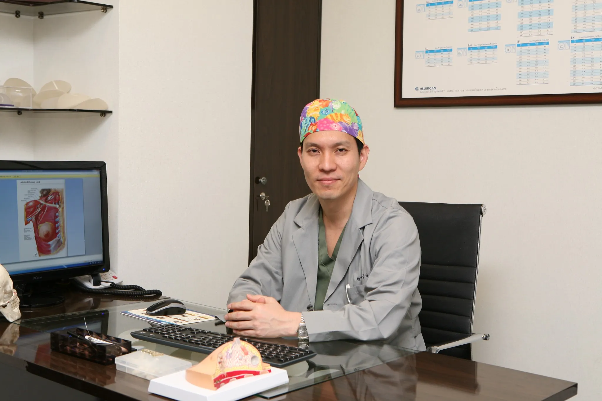 Board-certified plastic surgeon reviewing breast anatomy at his desk, where the risks of breast lift surgery are explained one to one.