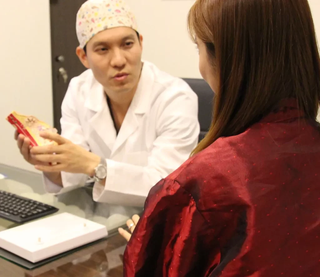 Plastic surgeon using a cross-section breast anatomy model to explain surgical options during a patient consultation, the starting point for planning breast reduction revision surgery.