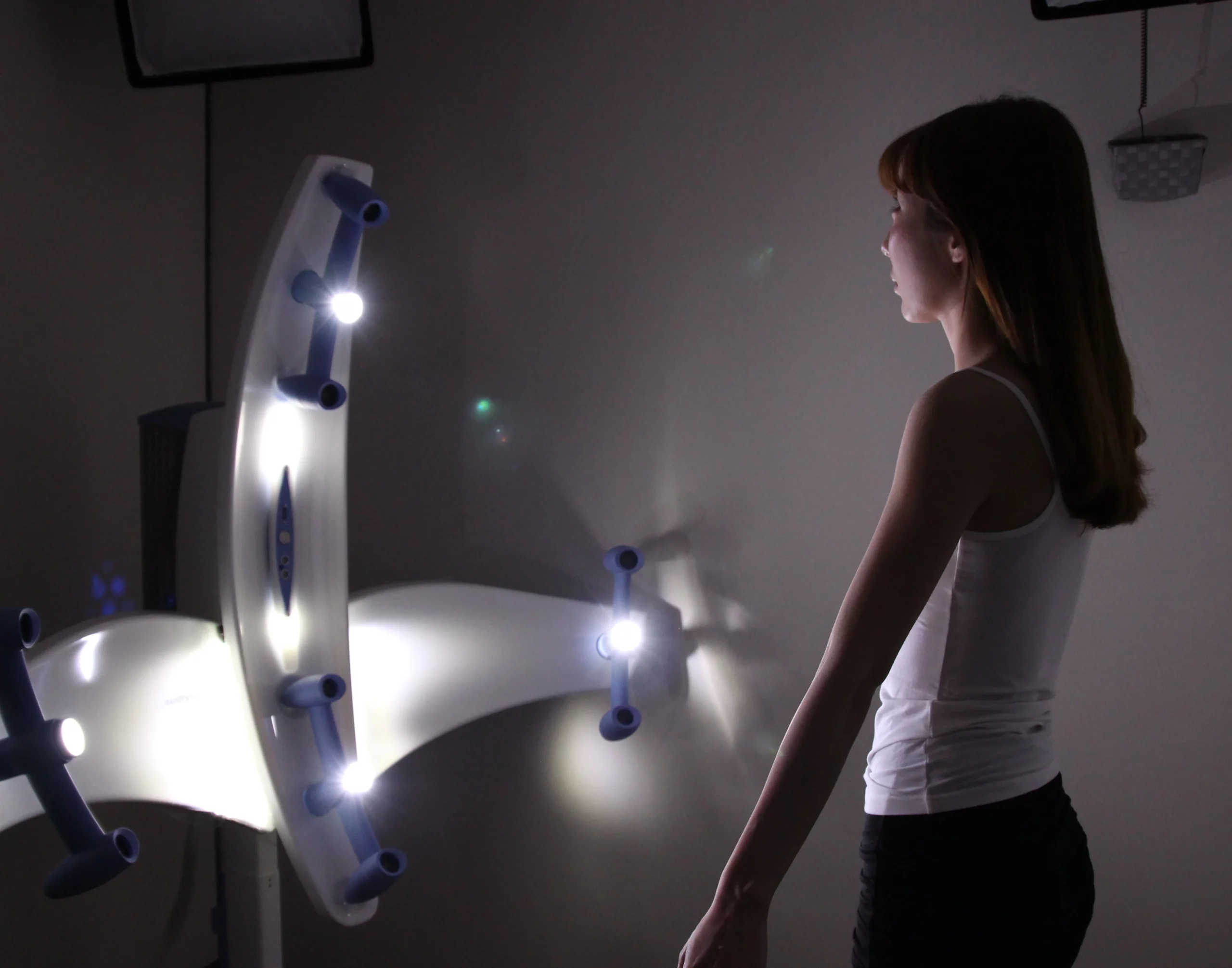 Woman standing in front of a multi-light 3D body analysis scanner used in breast consultations