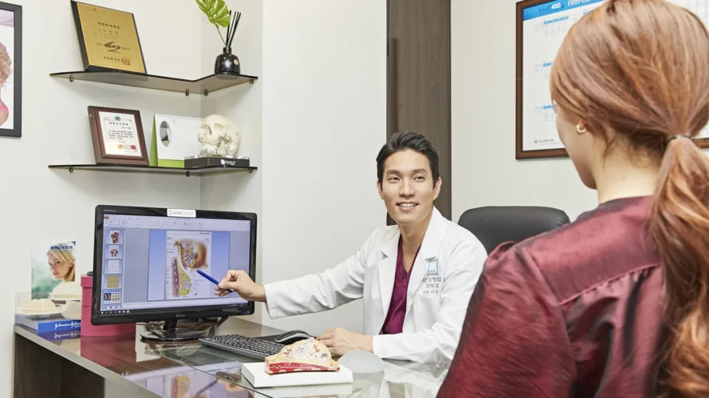 Surgeon explaining breast anatomy on screen to a patient during a consultation for breast implant revision after surgery abroad