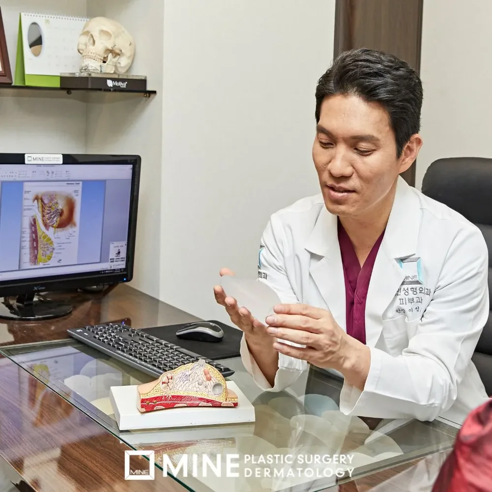 Surgeon explaining a breast implant and anatomy model during an in-person consultation at MINE Plastic Surgery in Seoul