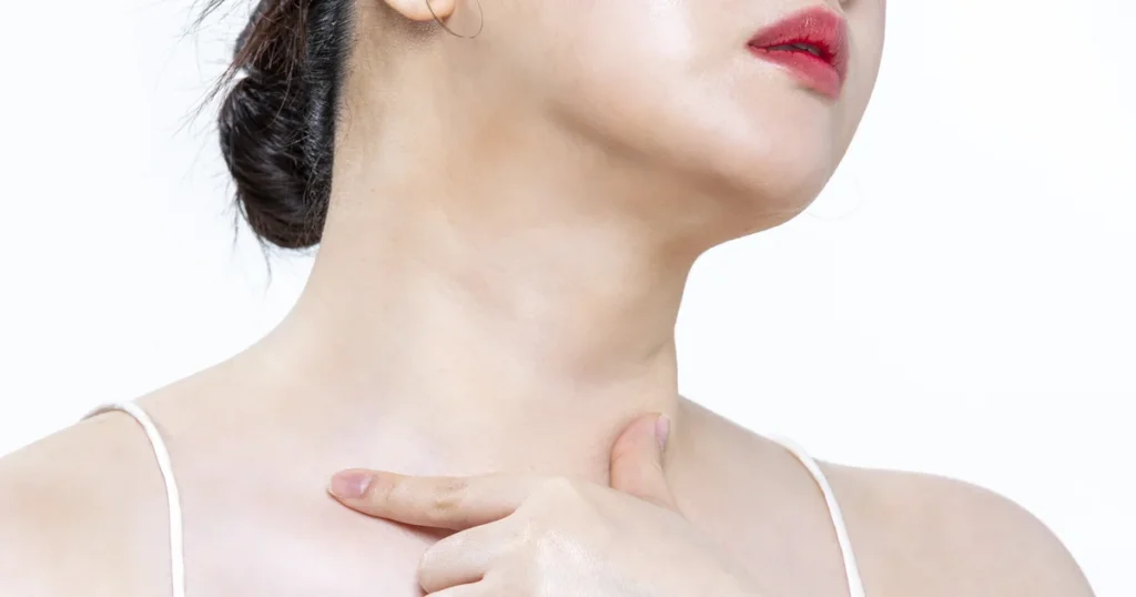 Woman with her head tilted up touching the front of her neck below the jawline, the area targeted by double chin exercises