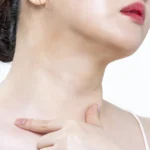 Woman with her head tilted up touching the front of her neck below the jawline, the area targeted by double chin exercises